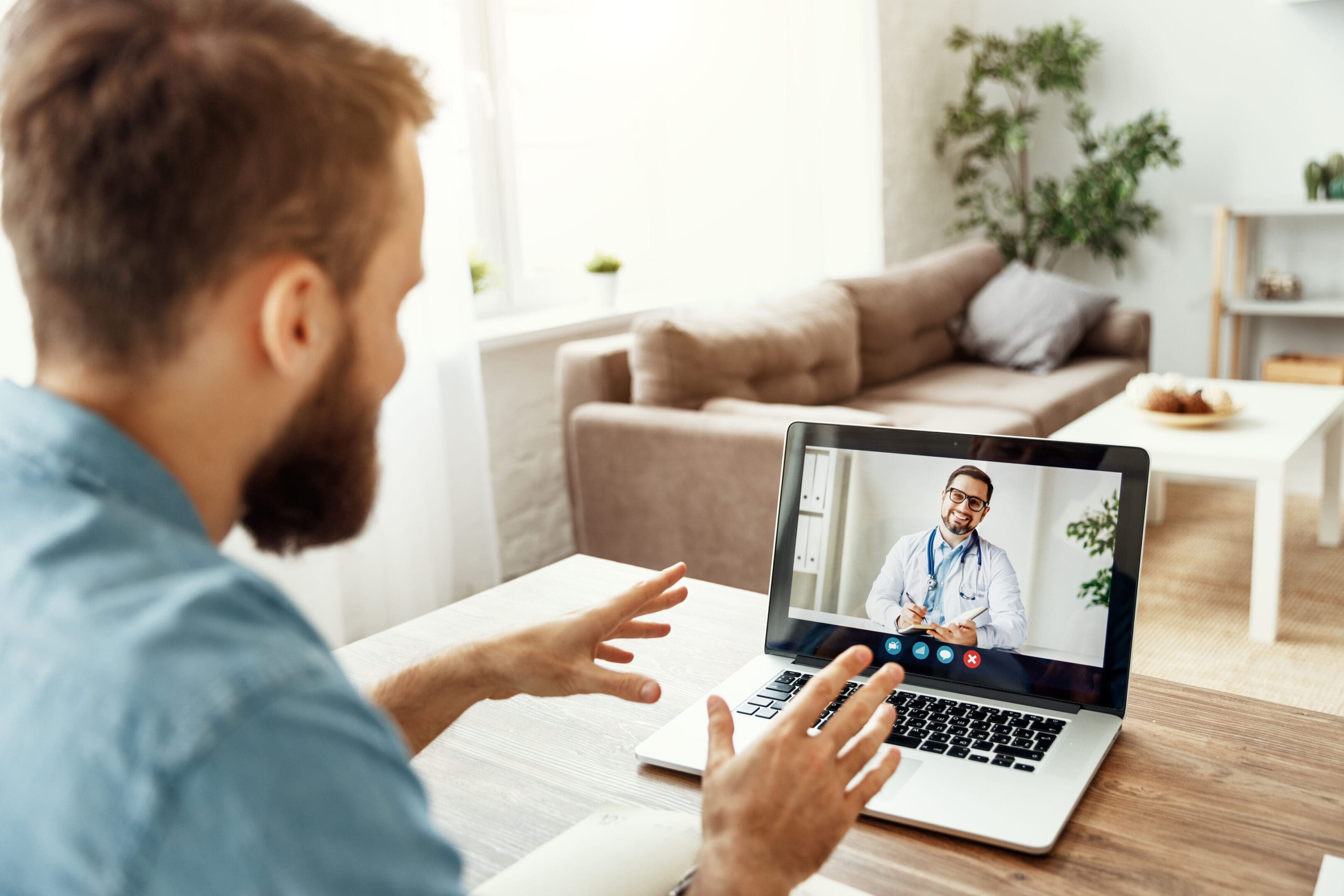 A man sitting at a table with his laptop and a video call.