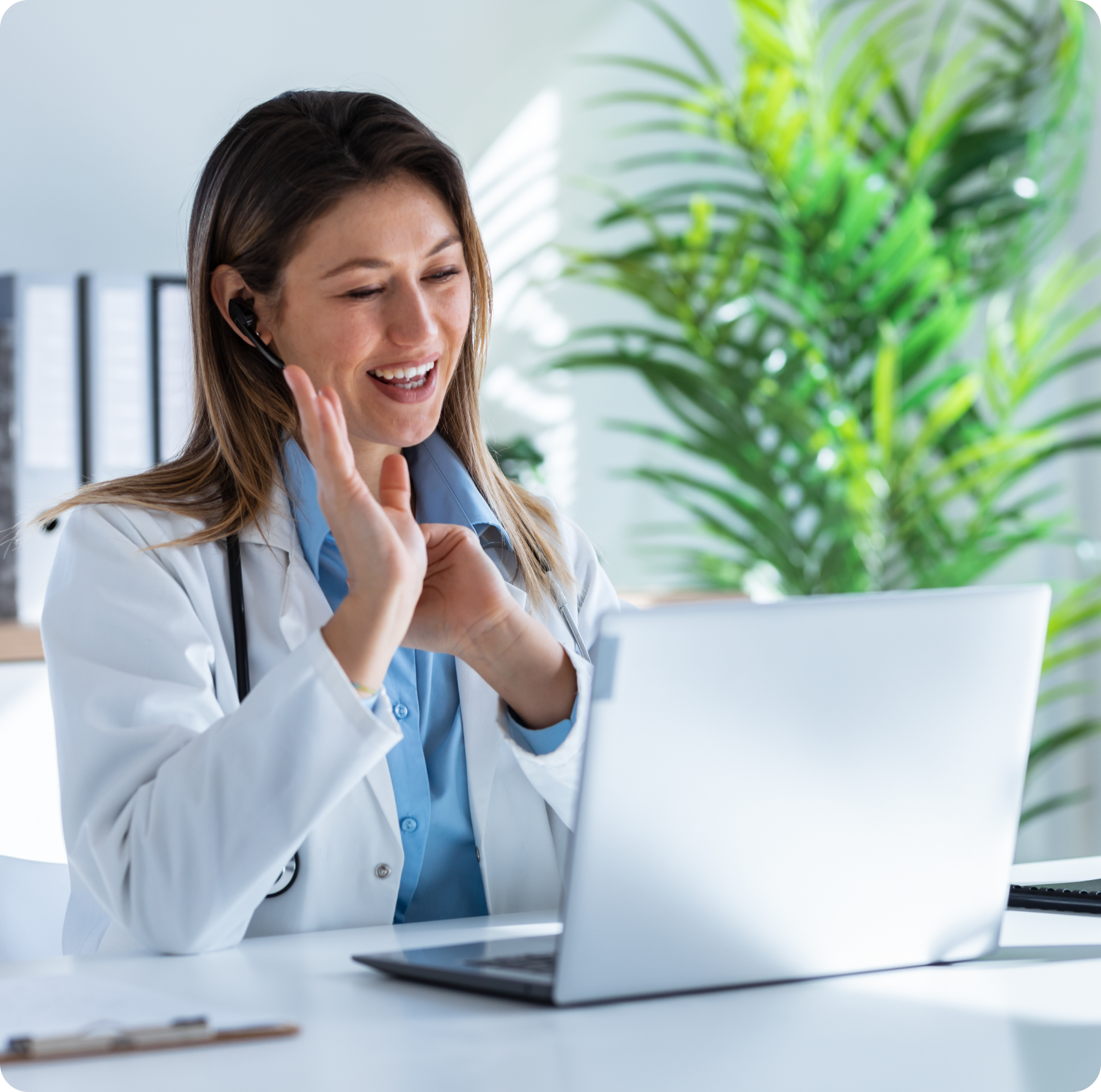 A woman in white lab coat sitting at table with laptop.