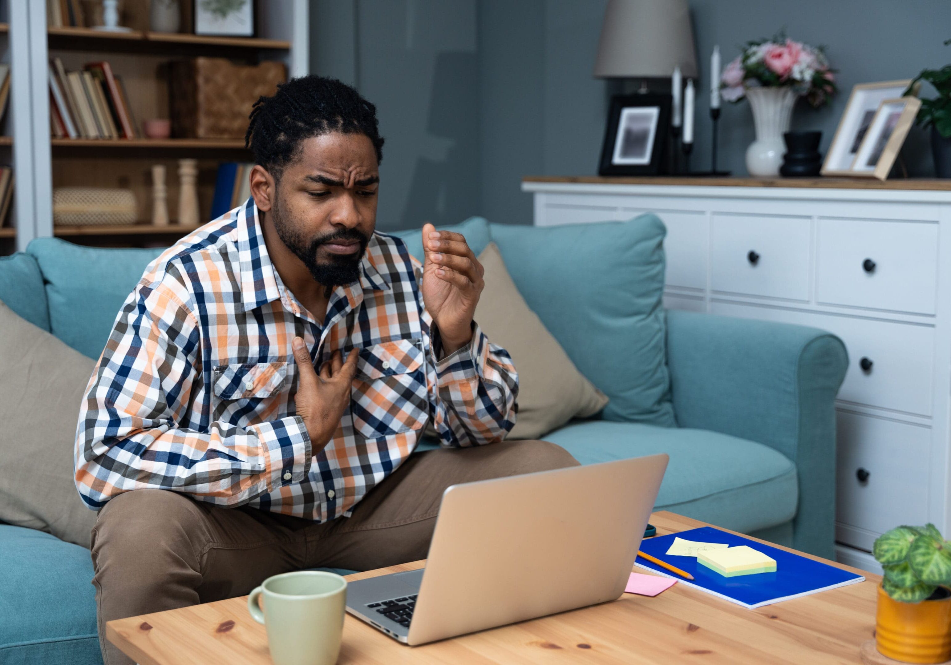 A man sitting on the couch looking at his laptop.