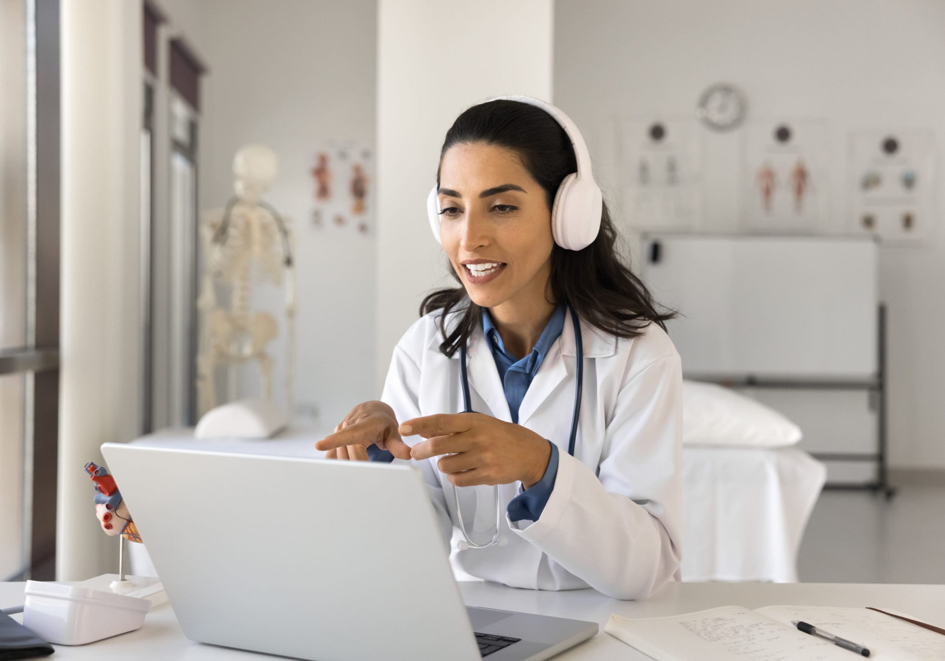 A woman wearing headphones and using a laptop.